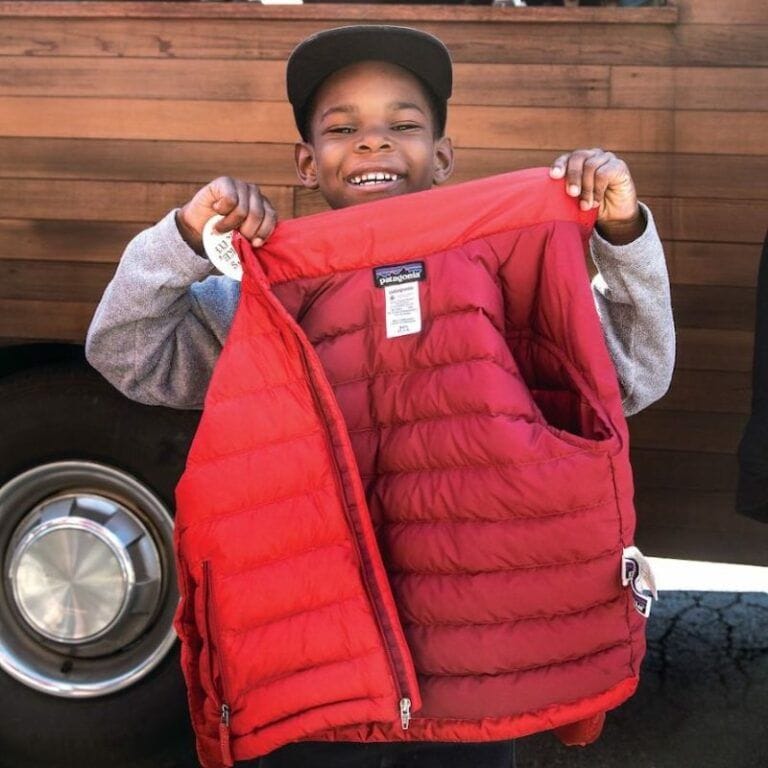 Young boy happily holding his repaired Patagonia red coat