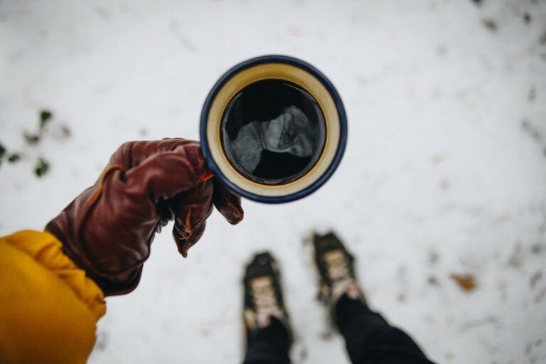 Hand holding a camping coffee mug viewed in first person perspective