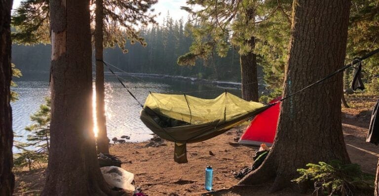 Hammock camping set up in the forest nearby a lake